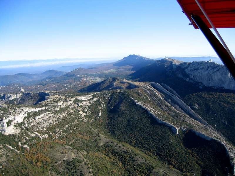 Vue aérienne sur un sommet montagneux, avec de la verdure et de la pierre beige