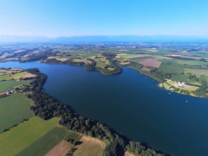 Vue aérienne sur le lac de Gabas, d'un bleu profond et entouré de champs verts et jaunes