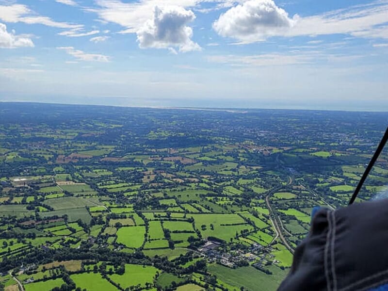 Vue aérienne sur les parcelles de champs vertes et ciel bleu et nuage à perte de vue.
