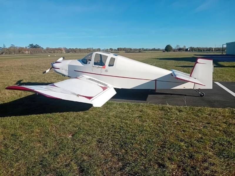 Un ULM Jodel D185A blanc, posé sur une piste entourée d'herbe.