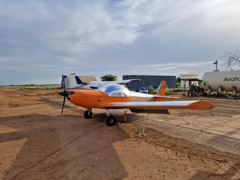Petit avion orange et blanc stationné sur une piste en terre lors d'un baptêmen en avion ULM aux Sables-d'Olonne.