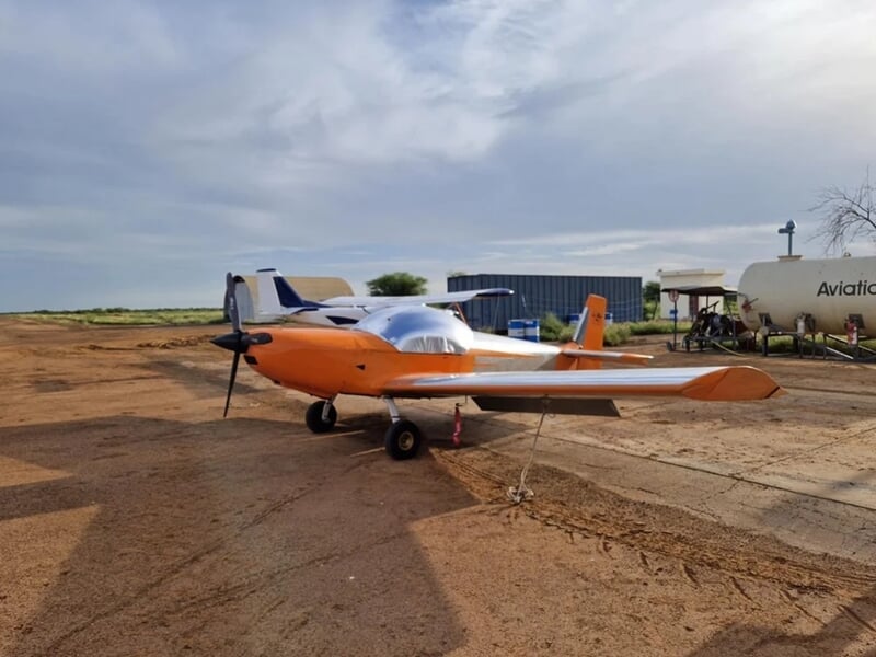 Petit avion orange et blanc stationné sur une piste en terre lors d'un baptêmen en avion ULM aux Sables-d'Olonne.