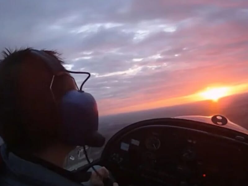 Pilote dans un petit avion au coucher du soleil, avec casque audio lors d'un vol en avion ULM près de Lille.