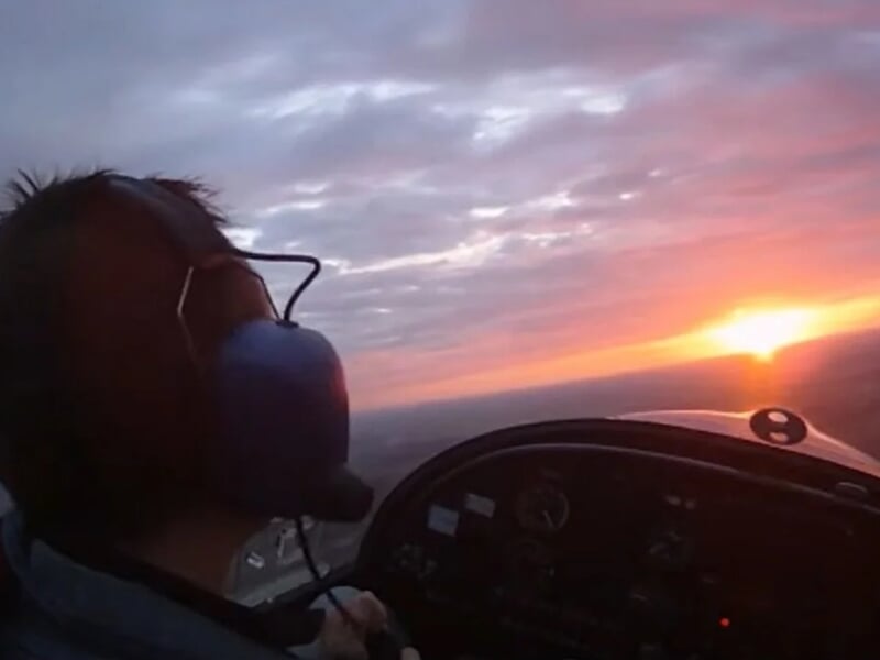 Pilote dans un petit avion au coucher du soleil, avec casque audio lors d'un vol en avion ULM près de Lille.