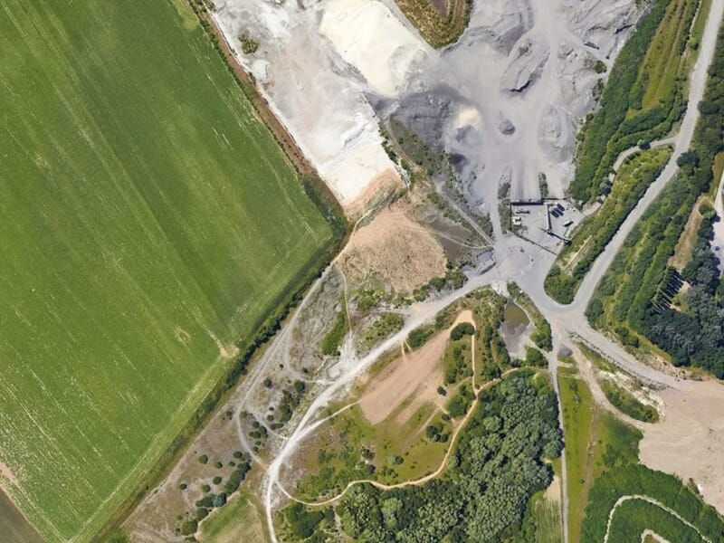 Vue aérienne d'un aérodrome avec des champs verts, des routes et des zones de terre lors d'un vol en autogire près de Reims.