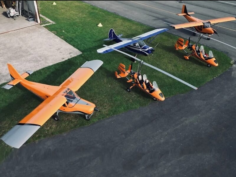 Plusieurs petits avions et ULM stationnés sur une piste d'aérodrome lors d'un vol en autogire près de Reims.