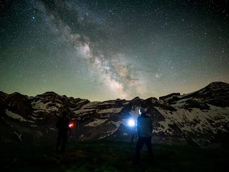 Deux photographes capturant la Voie lactée devant des montagnes enneigées