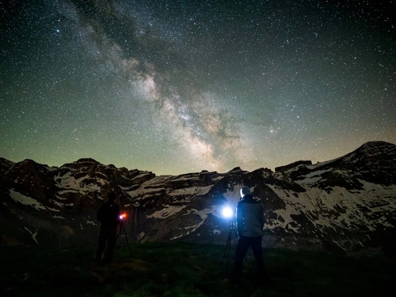 Deux photographes capturant la Voie lactée devant des montagnes enneigées