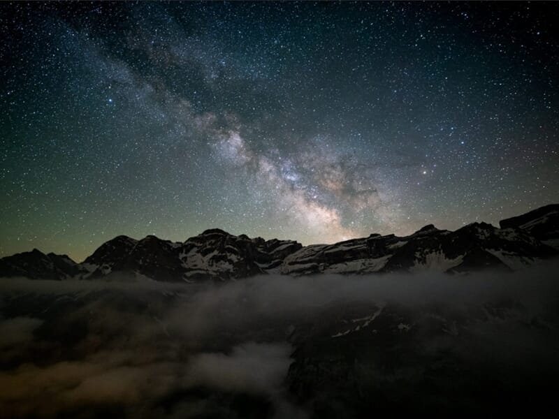 Ciel étoilé et Voie lactée au-dessus de montagnes et de brume nocturne