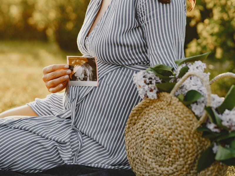 femme enceinte tenant une échographie, ambiance dorée en fin de journée.