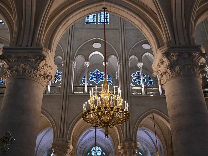 Vue intérieure d’une cathédrale gothique avec arcs en ogive, colonnes sculptées et vitraux colorés.