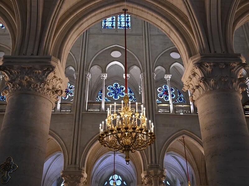 Vue intérieure d’une cathédrale gothique avec arcs en ogive, colonnes sculptées et vitraux colorés.