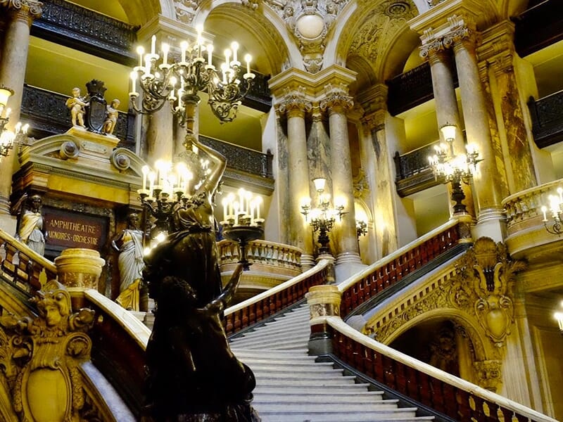 Grand escalier orné de statues et de lustres à l’intérieur de l’Opéra Garnier.