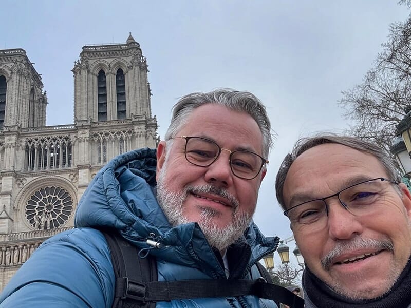 Deux hommes posent en selfie devant la cathédrale Notre-Dame de Paris.