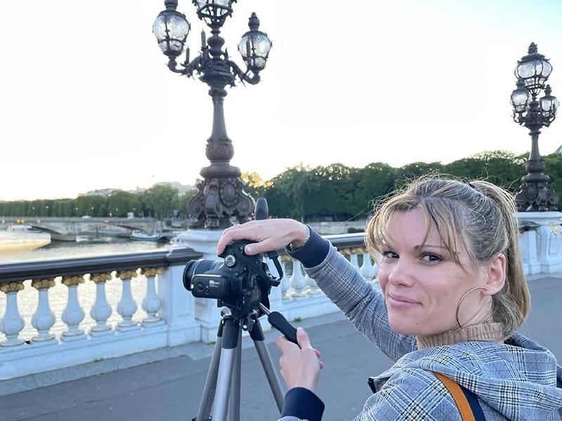 Femme en train de photographier avec un reflex numérique près du pont Alexandre III, à Paris, au bord de la Seine.