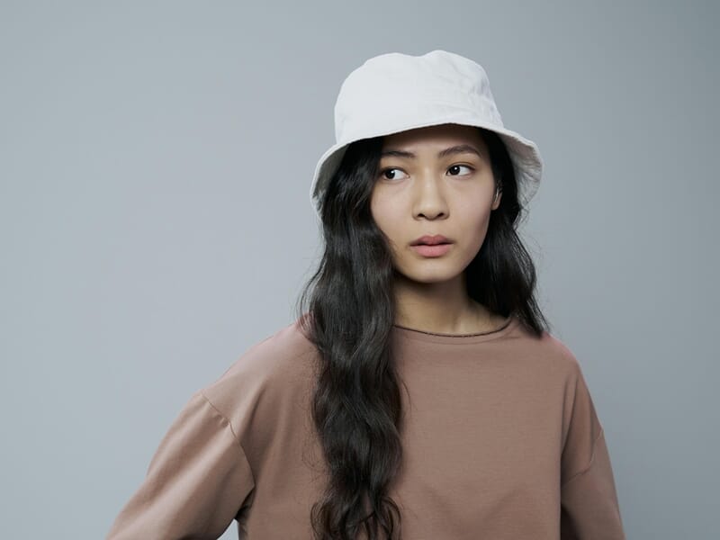 Femme en studio photo sur fond blanc avec un bob blanc et un top marron