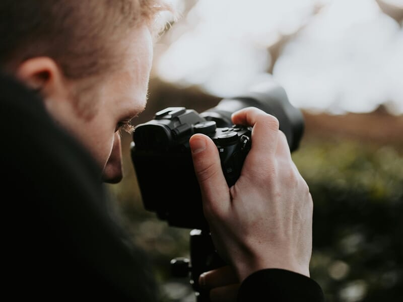 Homme utilisant un appareil photo dans un décor de campagne