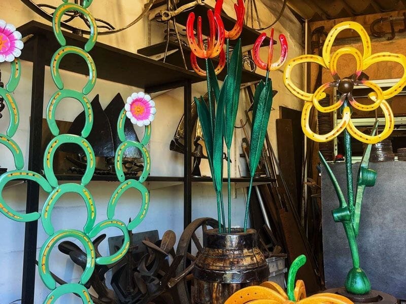Sculptures colorées en forme de fleurs et de fers à cheval exposées dans un atelier d'artisanat.
