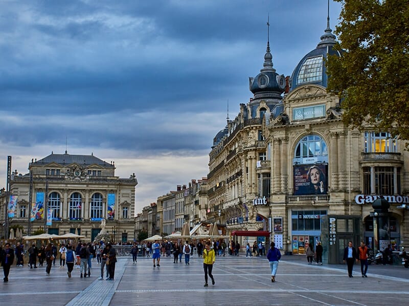Place de la Comédie à Montpellier, animée et bordée de bâtiments haussmanniens.