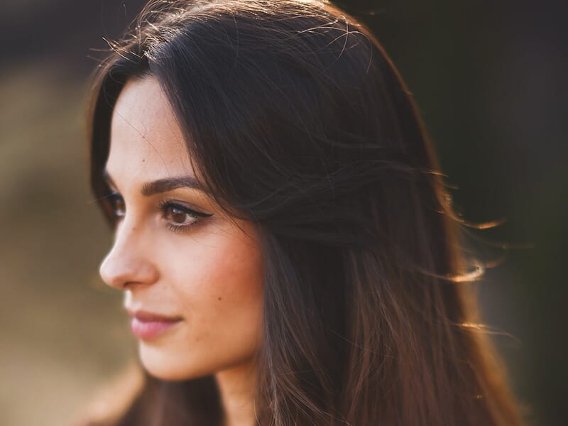 Portrait lumineux d’une femme de profil, avec des cheveux longs et lisses, regard tourné vers la gauche.