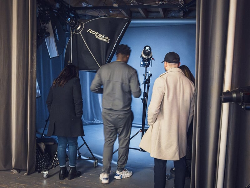 Groupe de personnes dans un studio photo avec éclairage professionnel.