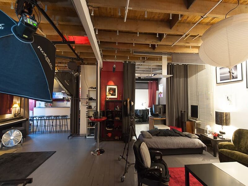 Vue large d’un studio photo aménagé comme un loft, avec zones de prise de vue, matériel, espace détente et mobilier chaleureux.