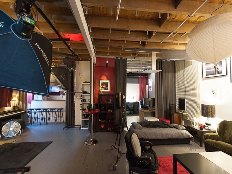 Vue large d’un studio photo aménagé comme un loft, avec zones de prise de vue, matériel, espace détente et mobilier chaleureux.