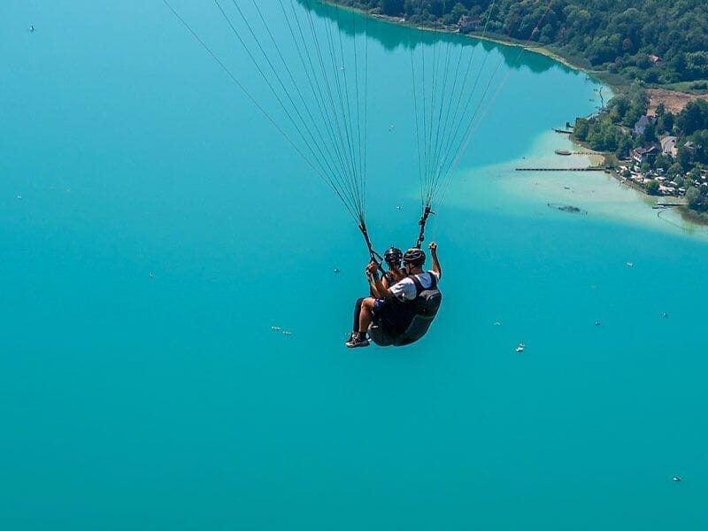 Vue rapprochée d'un baptême de parapente au-dessus du lac d'Aiguebelette avec deux personnes en vol.
