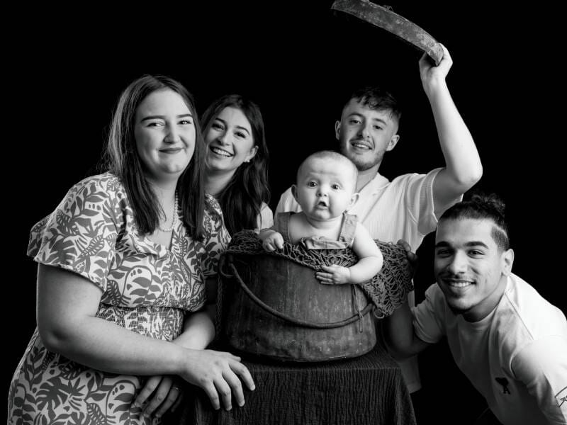 Photo en noir et blanc d'une femme et trois jeunes personnes, avec un bébé au centre.