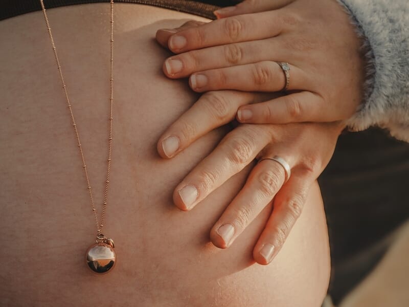 Gros plan sur un ventre de femme enceinte avec des mains posées dessus lors d'un shooting photo grossesse à Lille.