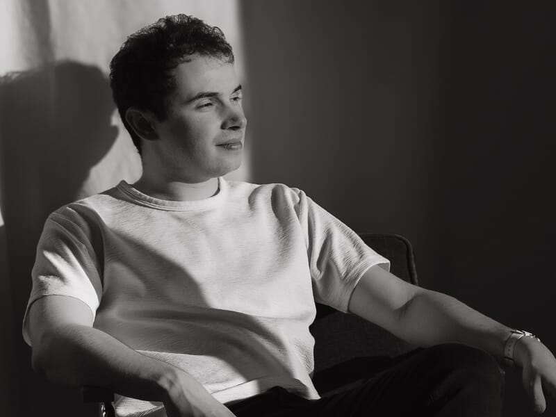 Jeune homme assis, regardant vers la lumière lors d'un shooting photo portrait sur la Côte d'Opale