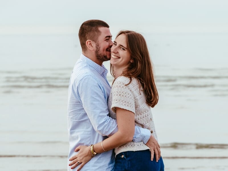 Un couple souriant s'enlace lors d'un shooting photo couple sur la Côte d'Opale.