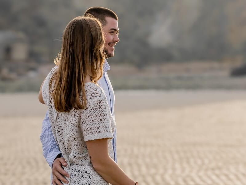 Un couple heureux se tient enlacé lors d'un shooting photo couple sur la Côte d'Opale.