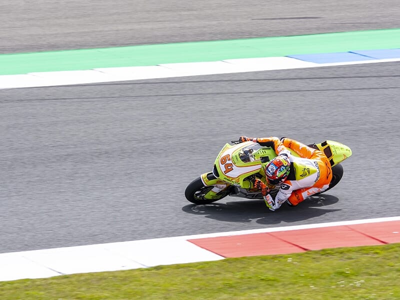 Motard en pleine courbe sur circuit, au guidon d’une moto jaune fluo numéro 54.
