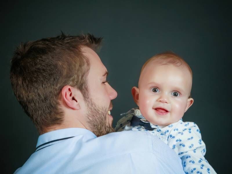 Un homme qui tient son bébé souriant dans ses bras.