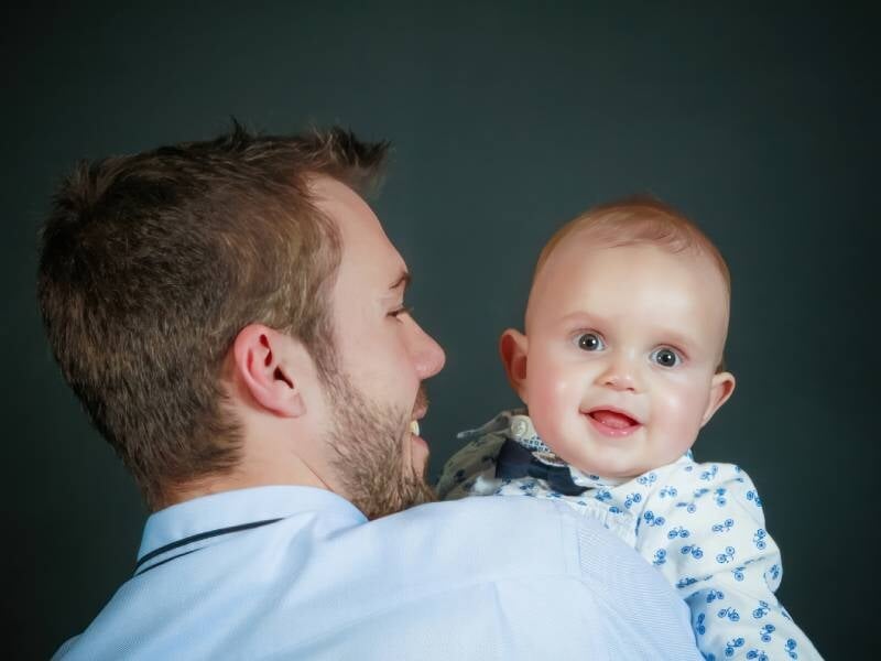 Un homme qui tient son bébé souriant dans ses bras.