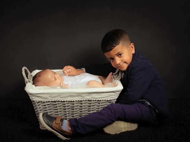 Un bébé dans un panier qui prend la pause avec son grand frère.