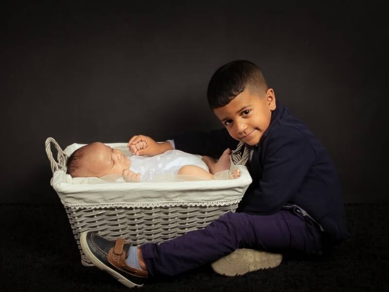 Un bébé dans un panier qui prend la pause avec son grand frère.