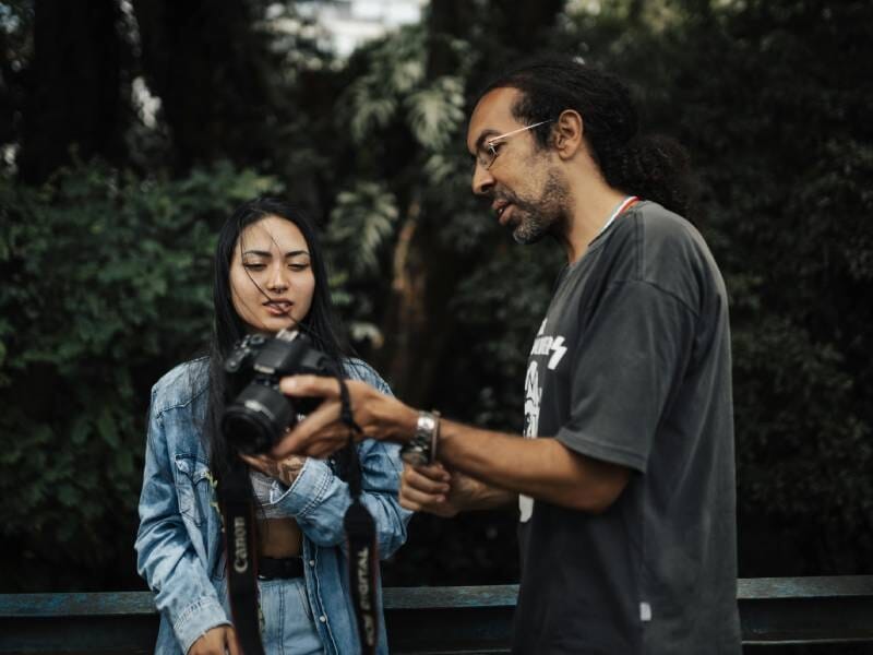 Un homme en train de montrer quelque chose sur son appareil photo à une femme.