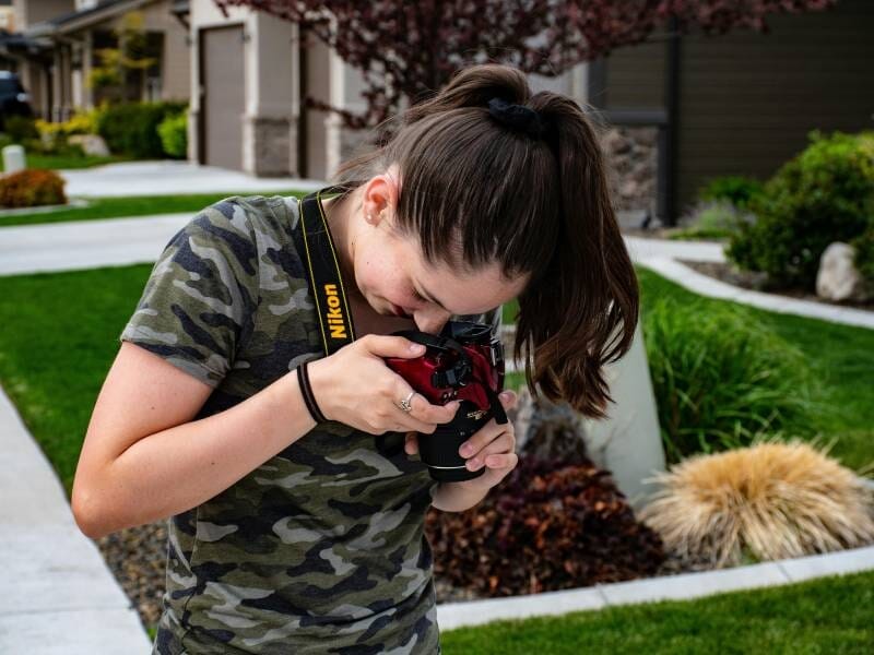 Une jeune femme prend une photo avec son appareil, objectif dirigé vers le sol.