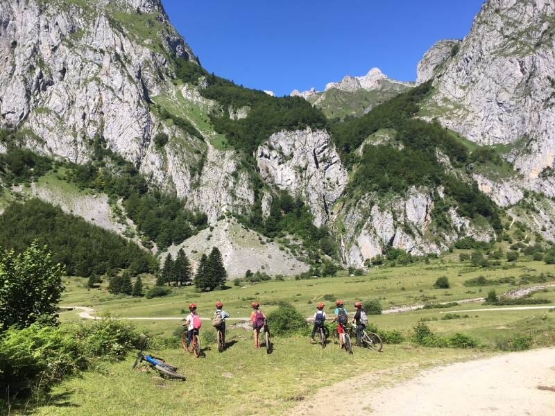 Des cyclistes en VTT sont à l'arrêt et observent la montagne devant eux.