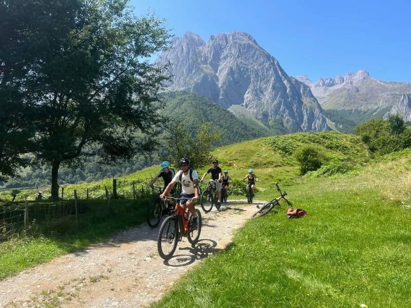 Cyclistes en VTT sur une piste de terre, au milieu de la montagne verdoyante.