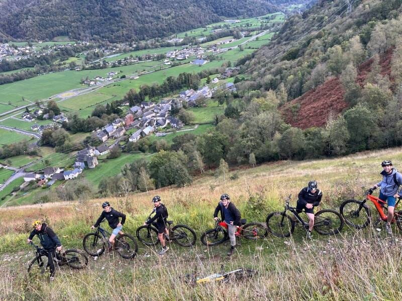 Un groupe de cyclistes prend la pose devant la vallée verdoyante.