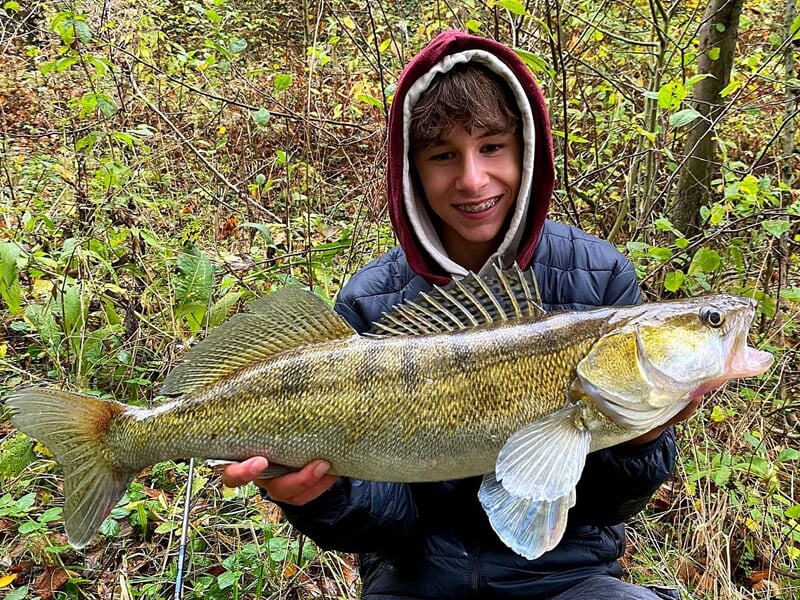 Jeune pêcheur souriant tenant un gros poisson lors d'un stage de pêche à Lille.