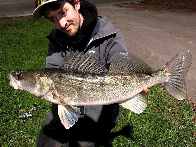 Homme en tenue de pêche tenant un grand poisson lors d'un stage de pêche à Lille.