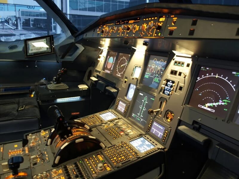 Poste de pilotage d’un avion de ligne avec écrans de navigation allumés et commandes activées