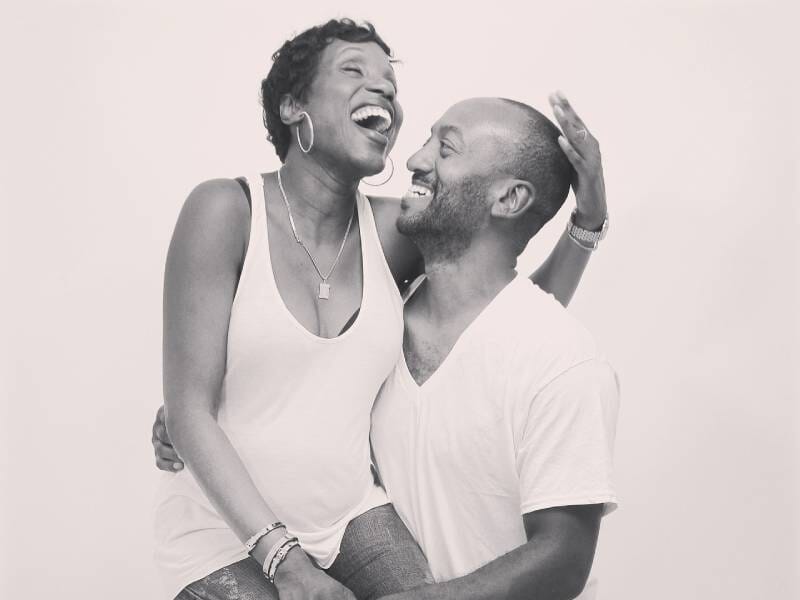 Un couple joyeux rit ensemble dans un studio, sur une photo en noir et blanc, partageant un moment de complicité et de bonheur lors d'un shooting à Orléans.