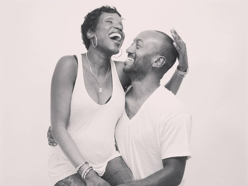 Un couple joyeux rit ensemble dans un studio, sur une photo en noir et blanc, partageant un moment de complicité et de bonheur lors d'un shooting à Orléans.