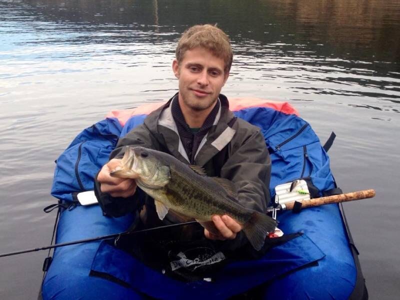 Une jeune homme sur un float tube présente un poisson.