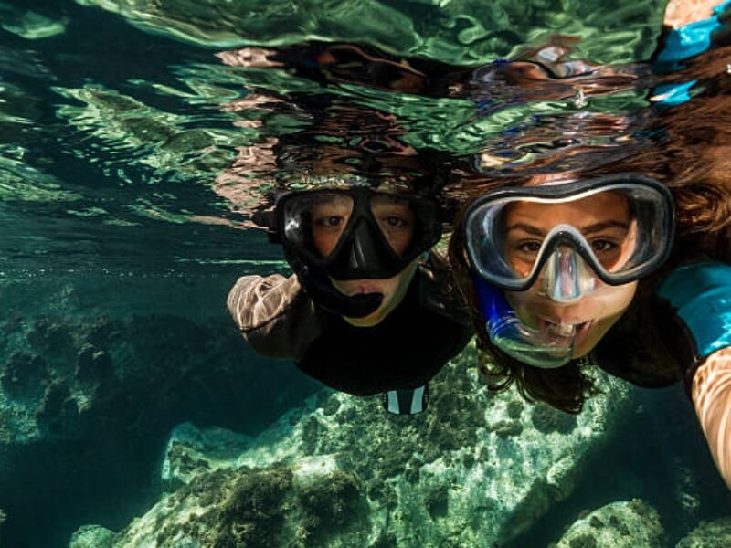 Deux nageurs en masque et tuba observant les fonds marins près de la surface.
